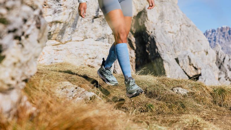 Beine mit Kompressionsstrümpfen beim Wandern auf einem Bergweg